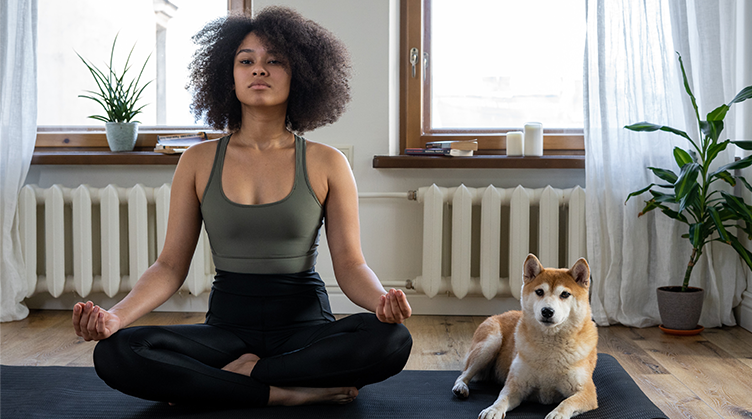 A-woman-practicing-yoga-with-her-dog-lying-next-to-her-1